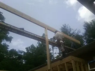 Carpenter setting a ridge beam over a new addition frame — Ice Dam Removal by Roofing Brothers in Longview
