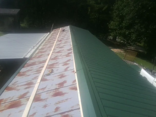 Old rusted panels beside newly installed green metal roofing — Wind Damage Roof Repair by Roofing Brothers in Longview