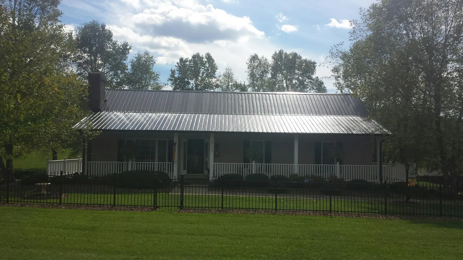 Gray metal roof on a brick ranch with a full width front porch — Gutter Guard Installation work by our crew in Longview
