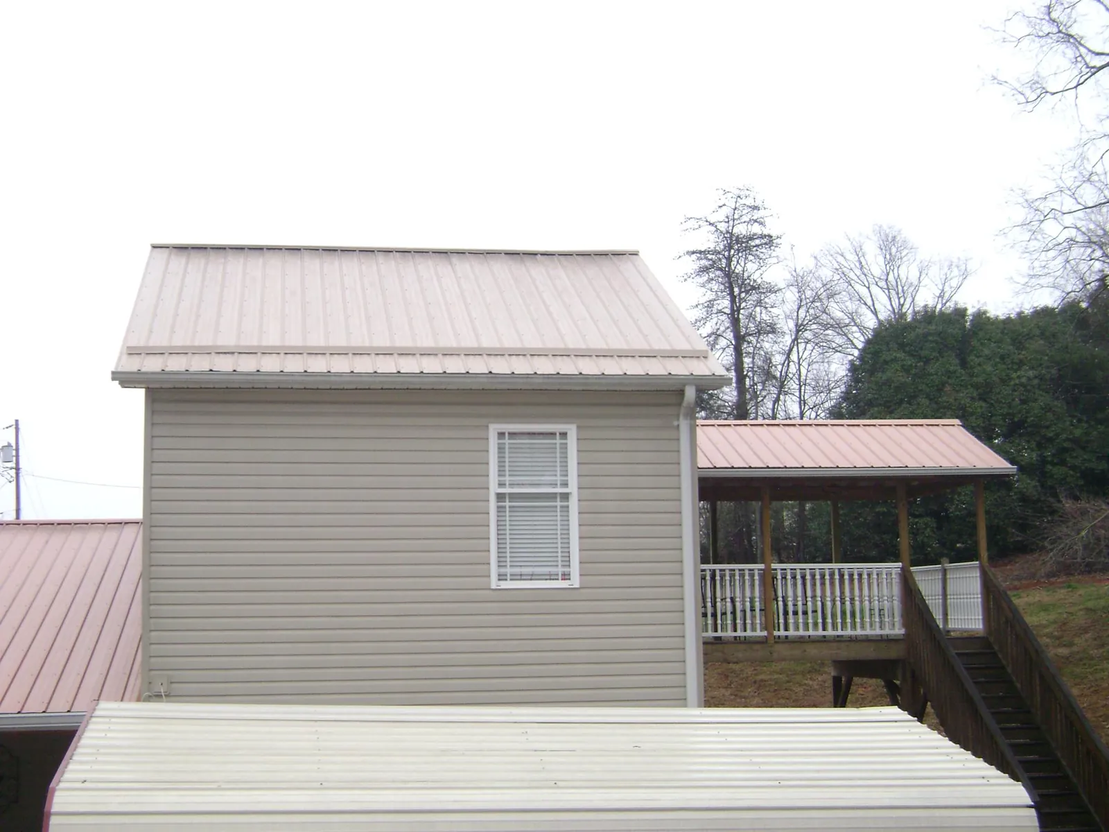 Tan metal roofs on a two story addition and attached porch, from a Roof Replacement job in Longview